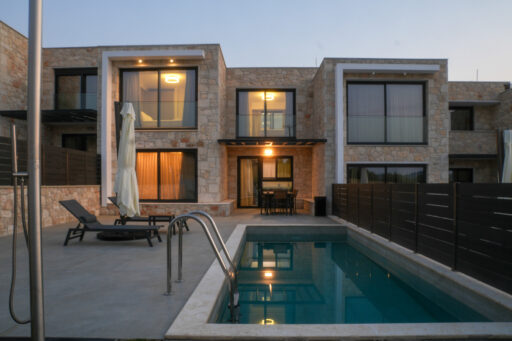 Illuminated private pool and exterior patio of the villa at dusk