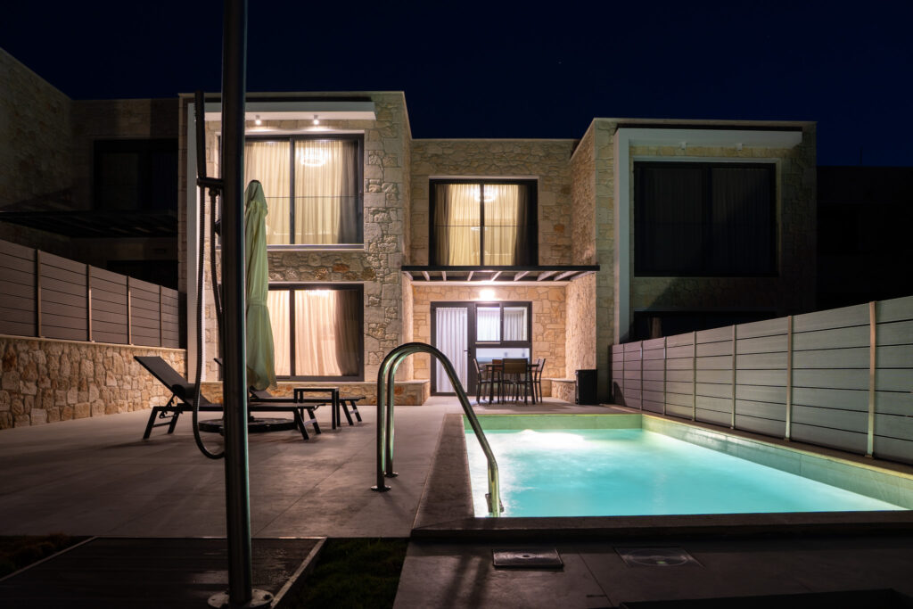 Nighttime view of The Olive Path villa, showing the illuminated private pool and outdoor dining area