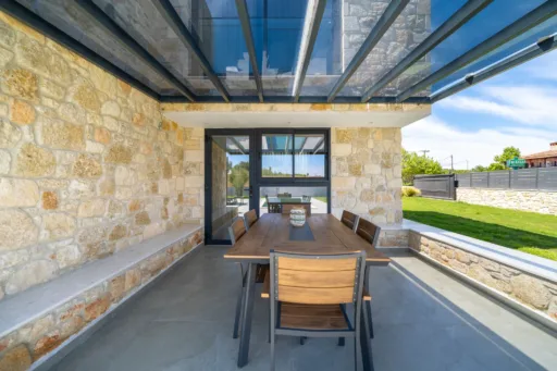 Outdoor dining area with wooden table and stone wall